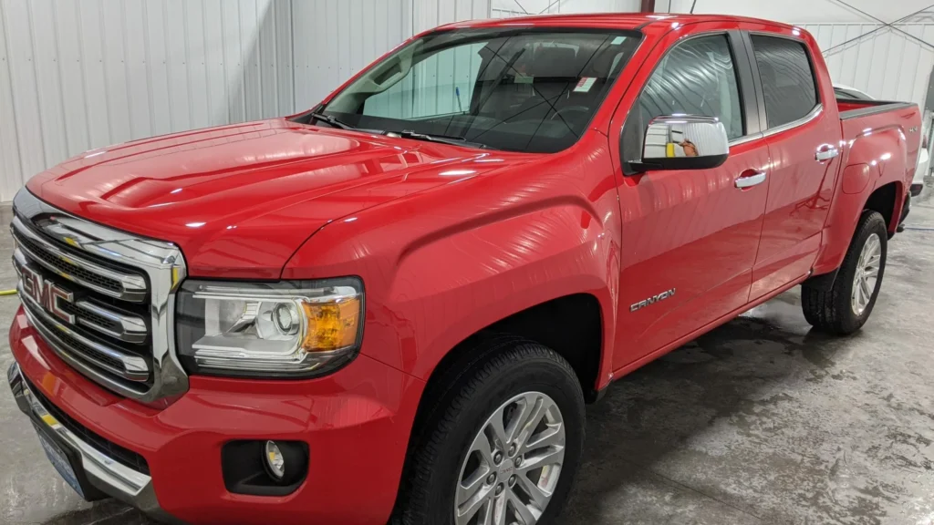 Side view of a red truck showing a deep, glossy finish achieved through expert hand wash, clay treatment, and premium waxing at Appleton Car Wash.