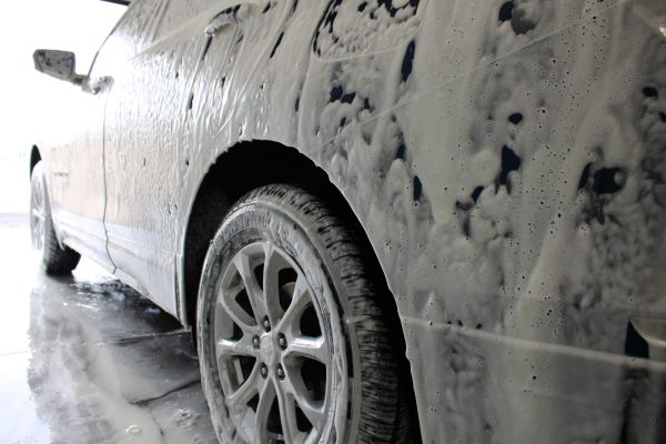 Foam car wash suds covering the vehicle for a deep clean.