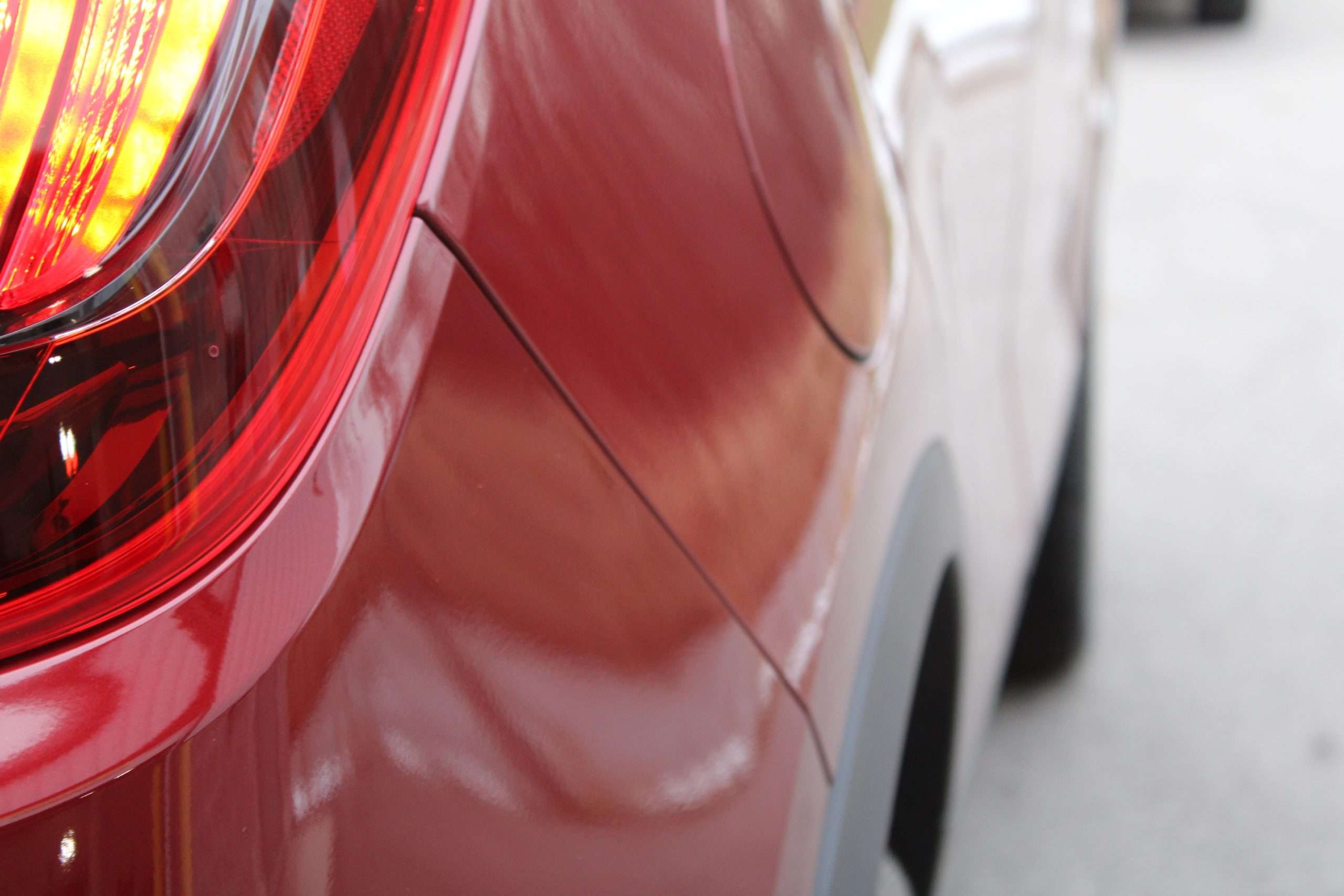 Close-up of a red vehicle's glossy paintwork after exterior detailing.