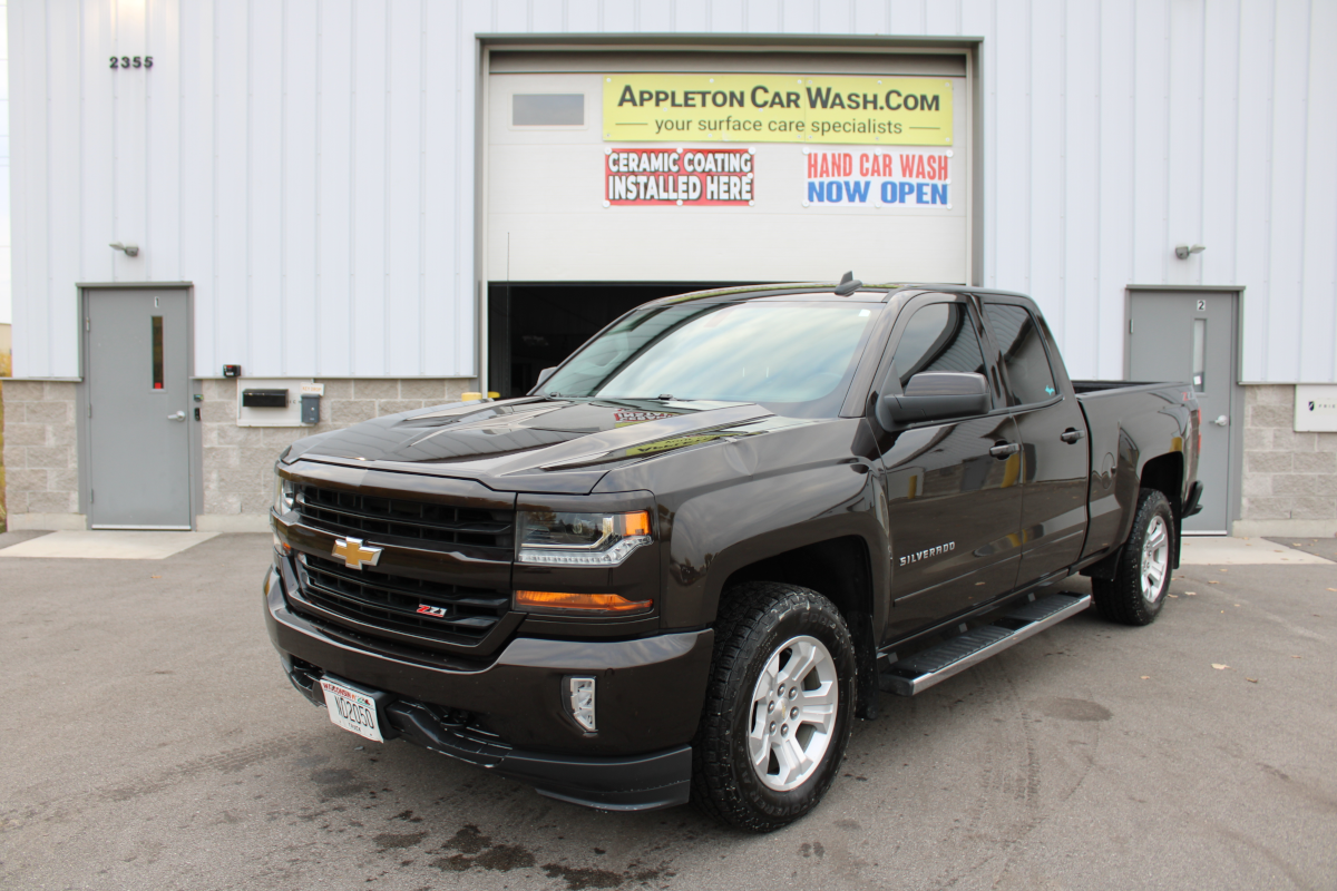 A freshly detailed black Chevrolet Silverado parked in front of Appleton Car Wash, showcasing a deep shine from our expert detail shop services.